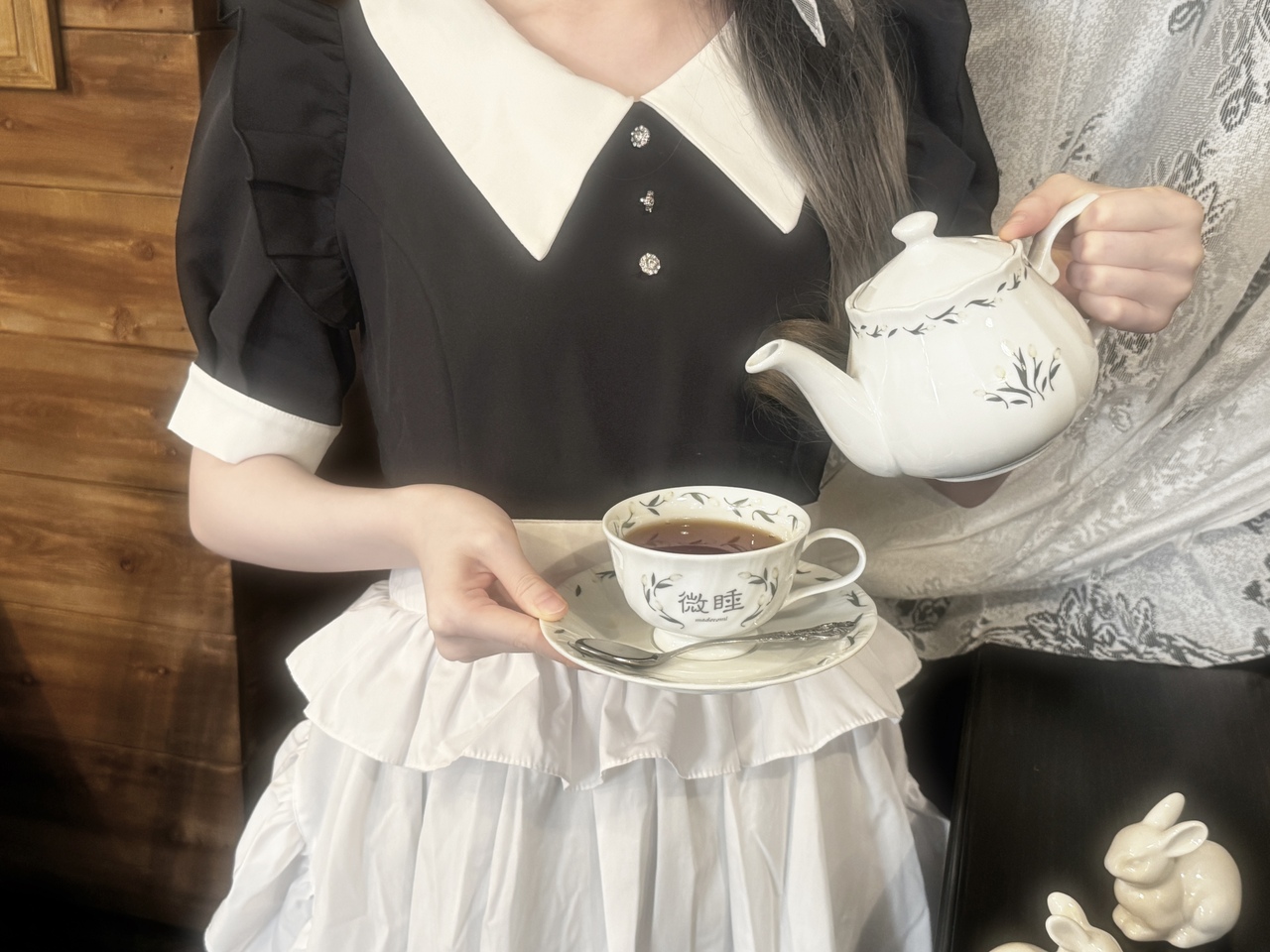 白いティーポットからカップへ紅茶を注ぐ喫茶 微睡のスタッフ